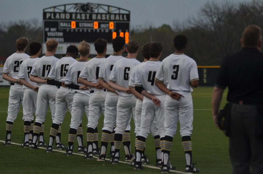 Baseball team stands during national anthem.