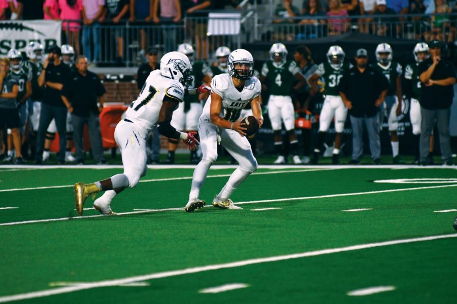 Driving down the field: Junior quarterback Dylan Hayden hands the football off to Senior running back Trey Scott-Jones during the Sep. 27 football game against Prosper High School. This run helped set up a missed field goal attempt in the first quarter. Photo by Morgan Brown.