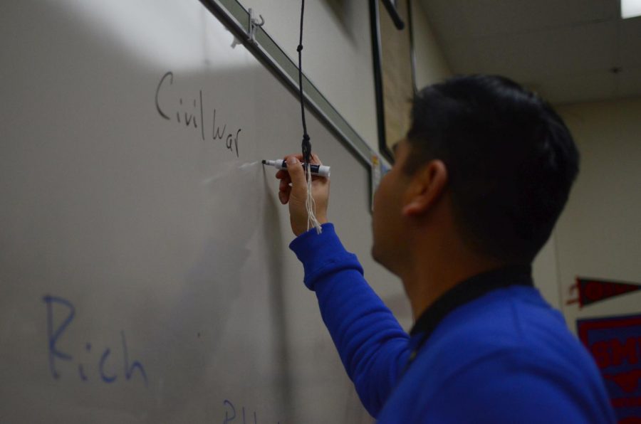  U.S. history teacher Dean Malabanan writes notes on the Civil War in class Dec. 13. Malabanan balances teaching with pursuing additional education. "Imagine trying to do your course here and then you have to do homework for your [other] two classes," Malabanan said. "It’s a balance that you just have to find."