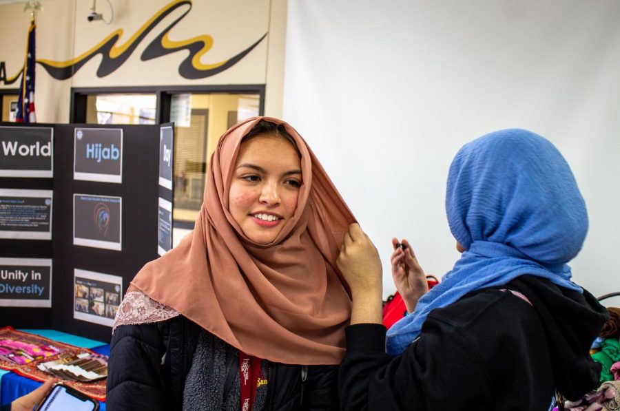 Freshman Mehreen Syed helps senior Lizzie Mortel tie a headscarf. Mortel wore the hijab along with her friends throughout the day. “I thought that it was very eye-opening and involving,” Mortel said. “I felt like I was a part of a family.”