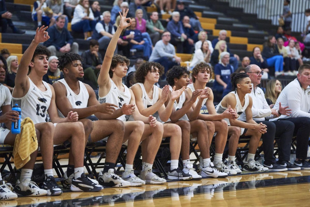 The varsity basketball team cheers on their teammates as they attempt to make a 3-pointer.