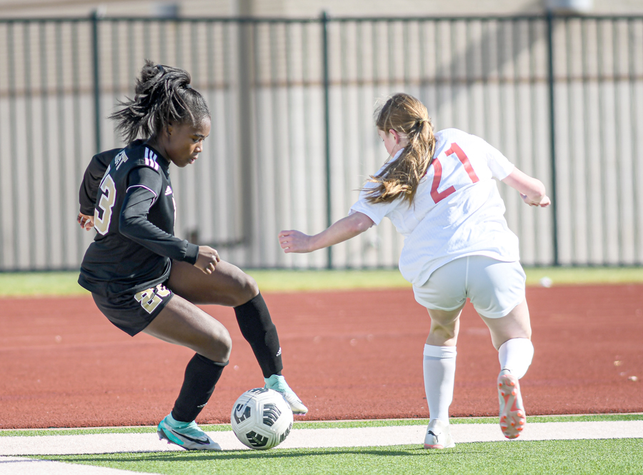 Peyton Cooper (23) protects the ball from a Lady Cardinal in Plano East’s 6-1 win over John Paul II. The girls won two of their three games at the Andie Studley Memorial Showcase in Wylie last week.